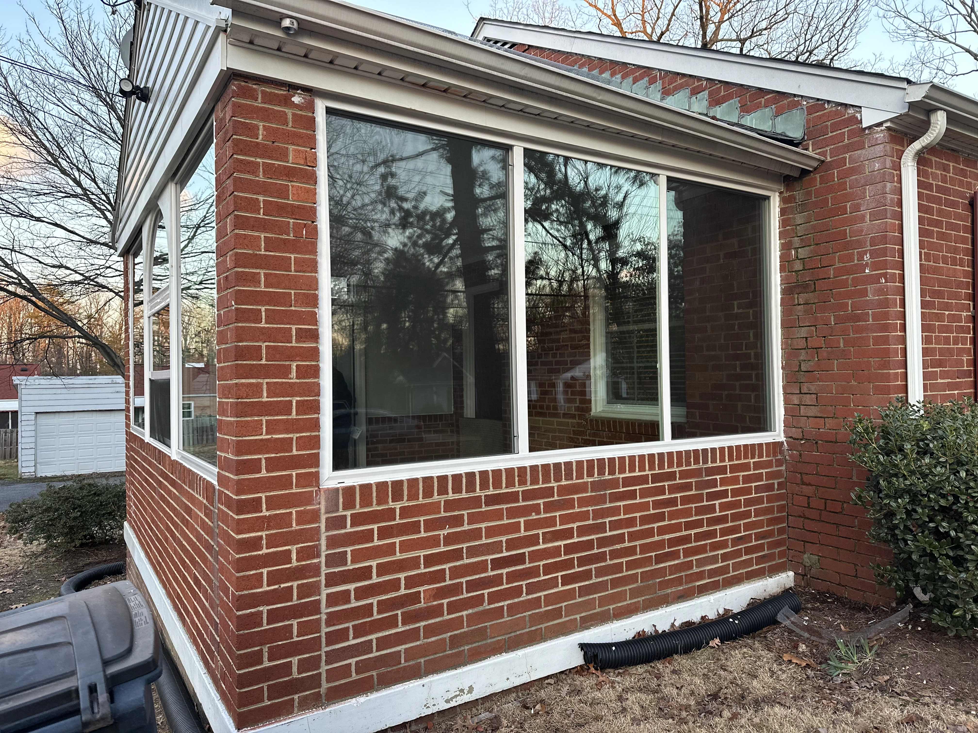 A brick house featuring a single window with a detailed window frame.