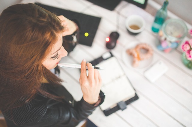 woman biting pen at desk