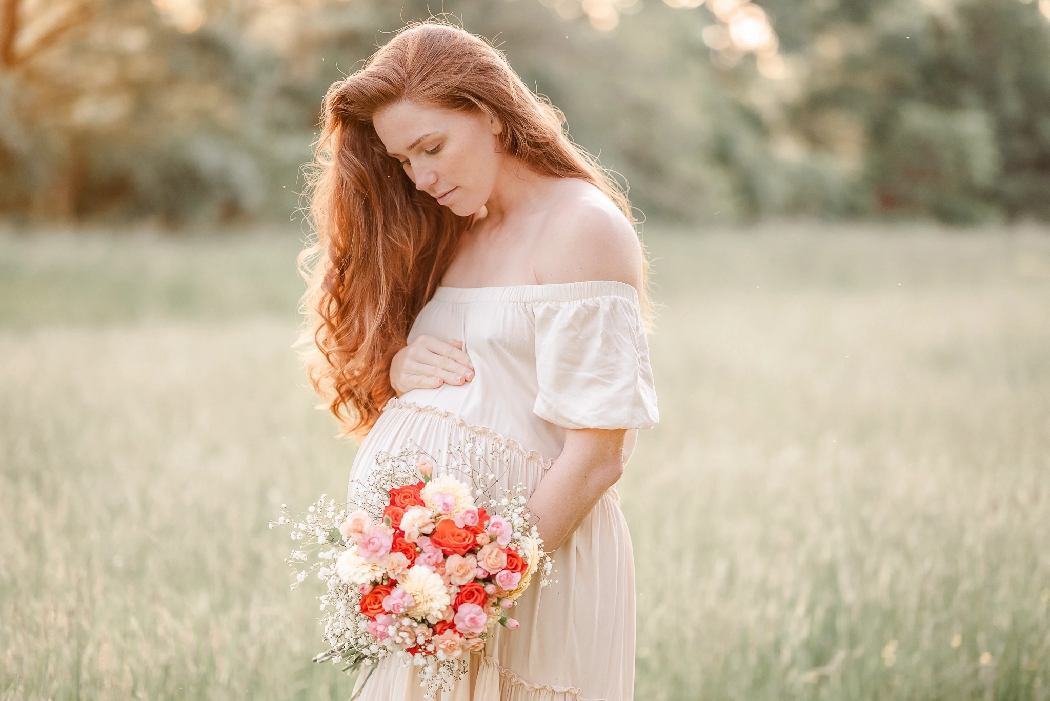 An expectant mother stands in a field during her maternity session with Virginia Beach photographer, Justine Renee Photography. She is wearing a flowy beige dress and holidng a colorful bouquet.