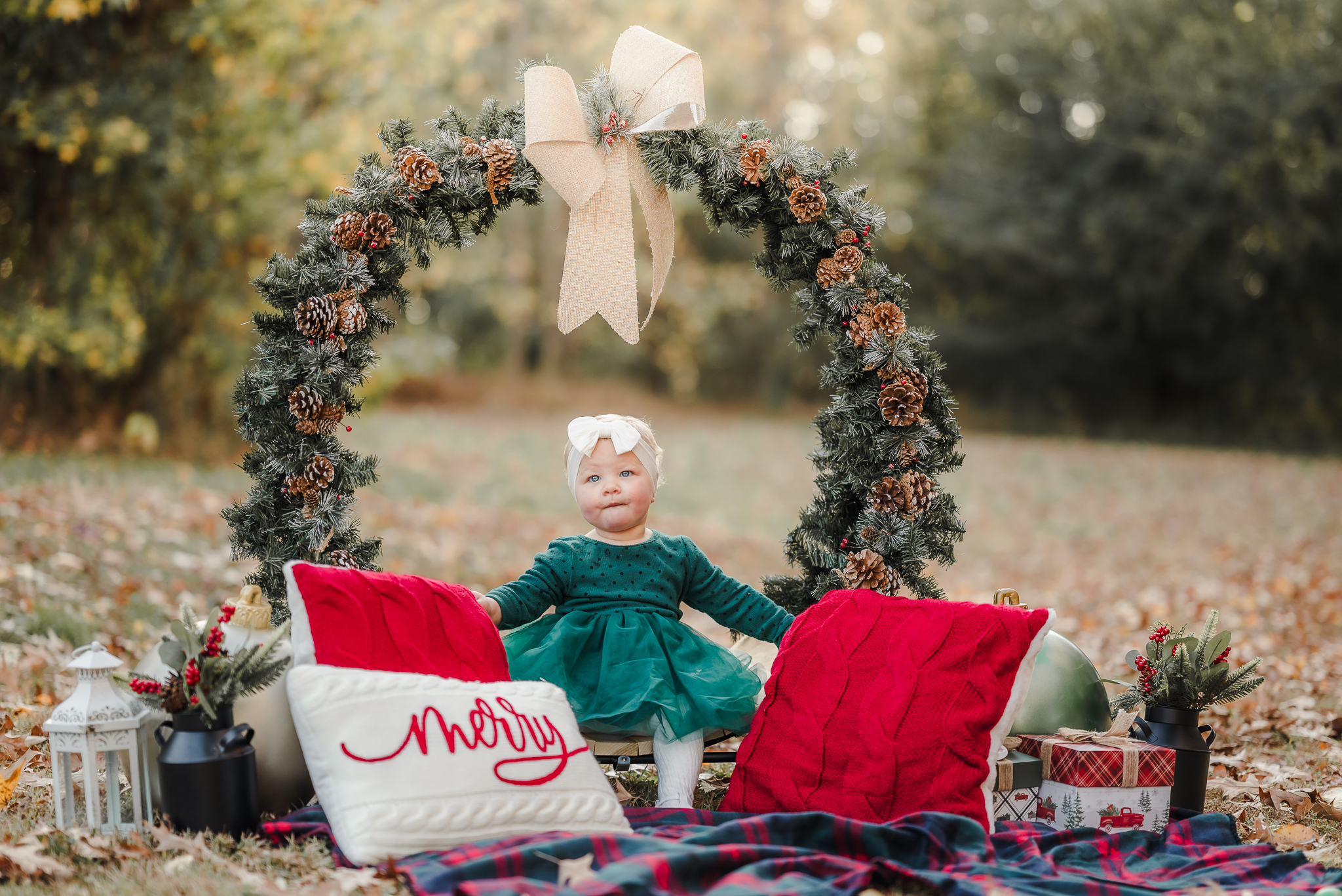 A toddler sits in a giant wreath during her Christmas mini session in Chesapeake