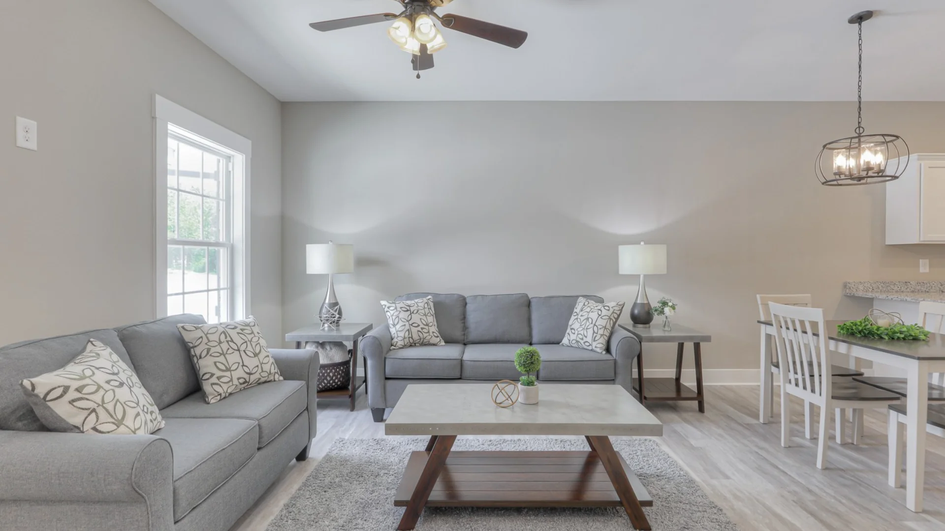 Legacy Townhomes living room with open floor plan, modern gray sofas, dining space, and natural light in Manchester, TN.
