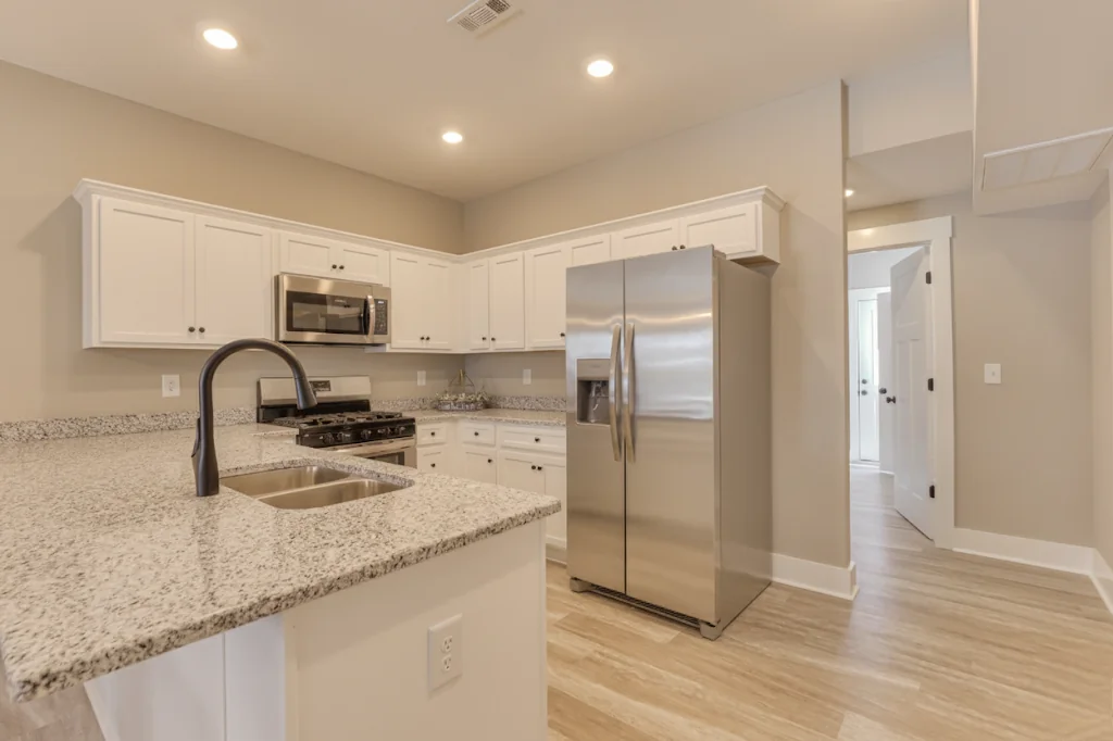 Legacy Townhomes kitchen with granite countertops, stainless steel fridge, oven, and modern white cabinetry in Manchester, TN.