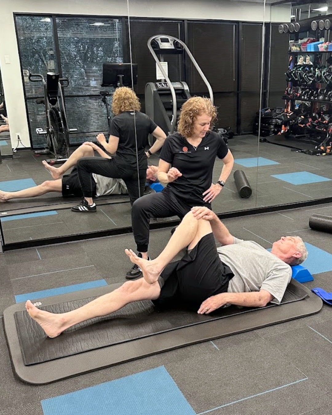 A man and his coach performing a leg stretch in a personal training in a gym, demonstrating fitness and flexibility exercises. A man and his coach performing a leg stretch in a personal training in a gym, demonstrating fitness and flexibility exercises.