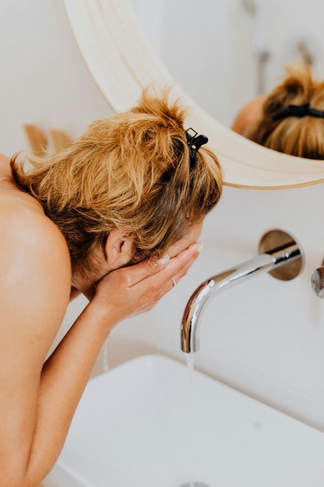 women washing face in mirror. women washing face in mirror.