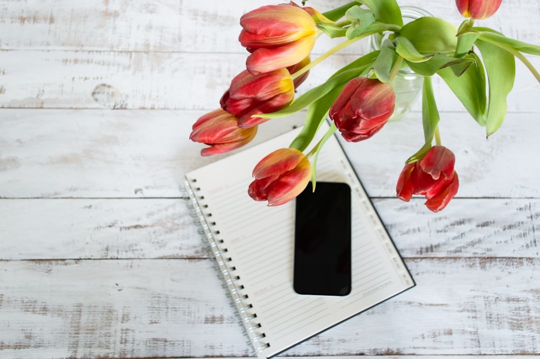 bunch of flowers on a table with a phone and planner bunch of flowers on a table with a phone and planner