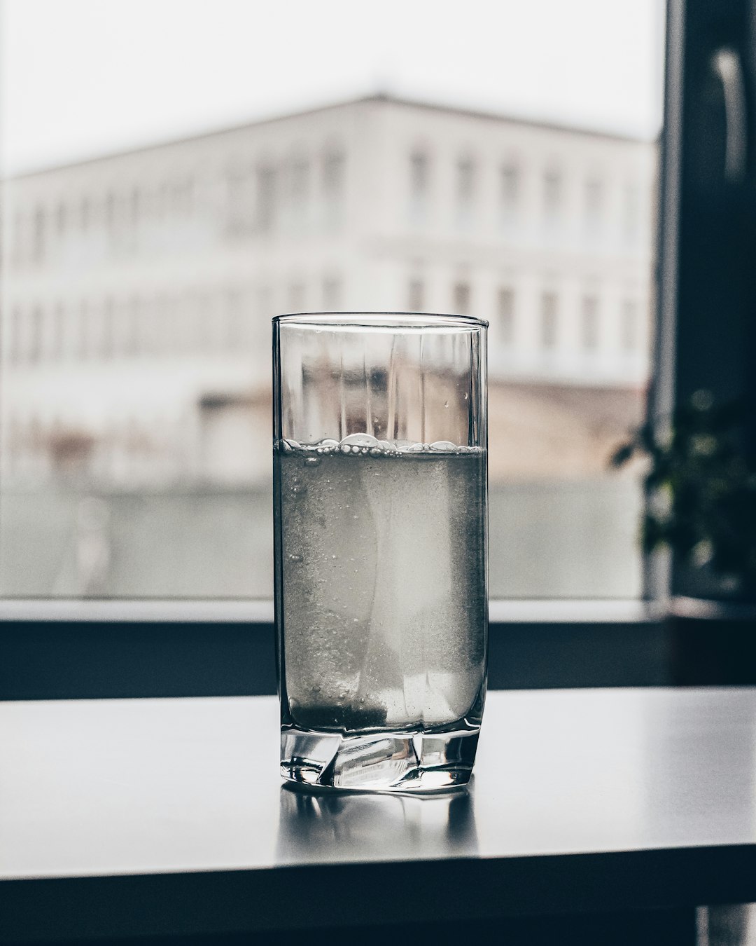 glass of water on window sill with city in background glass of water on window sill with city in background