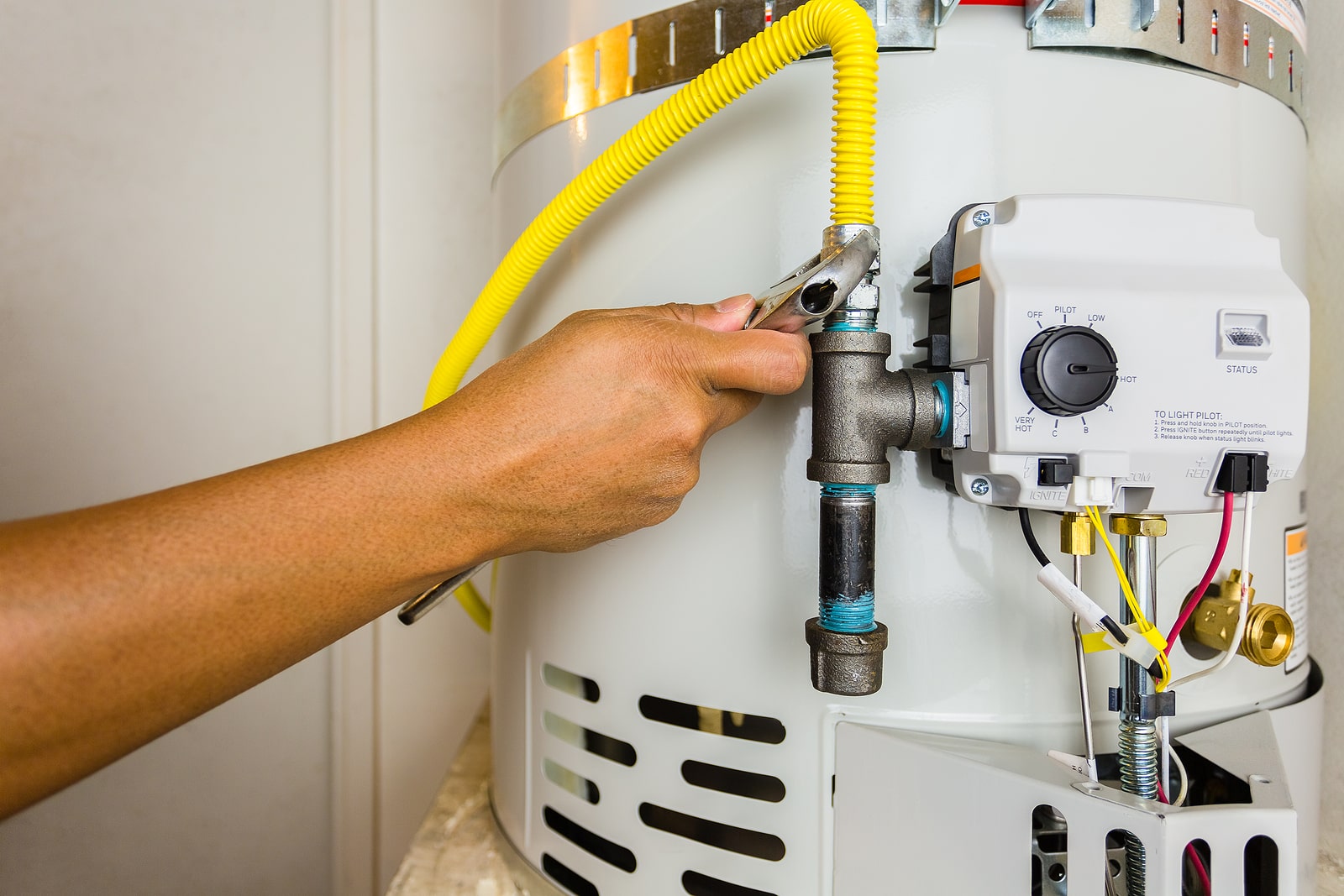 a hand holding a wrench and connecting a hose to a heater