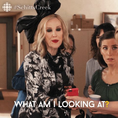 Schitt's Creek gif of Moira Rose looking at a cell phone and asking "What am I looking at?"