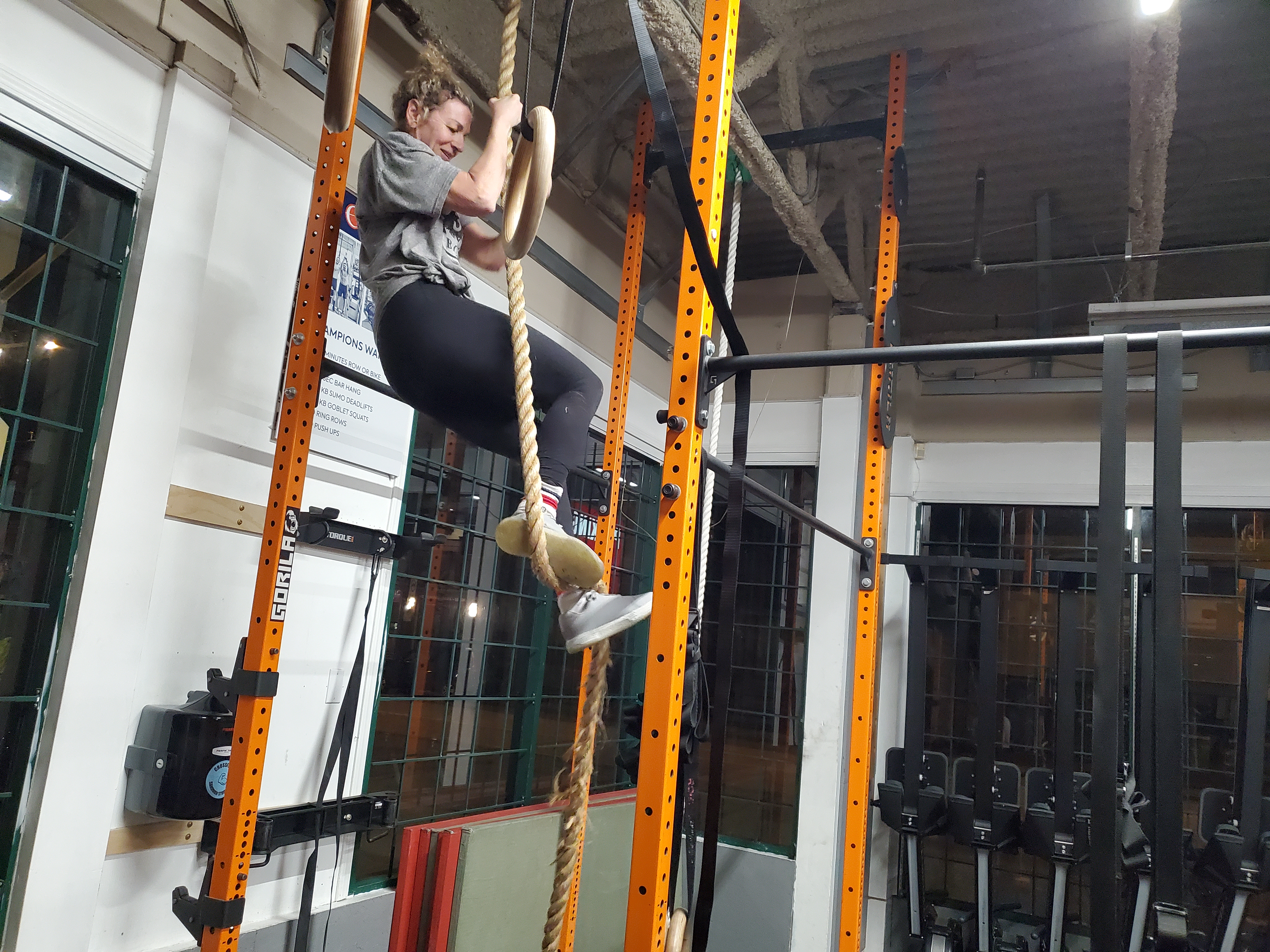 Woman climbing a rope in the gym