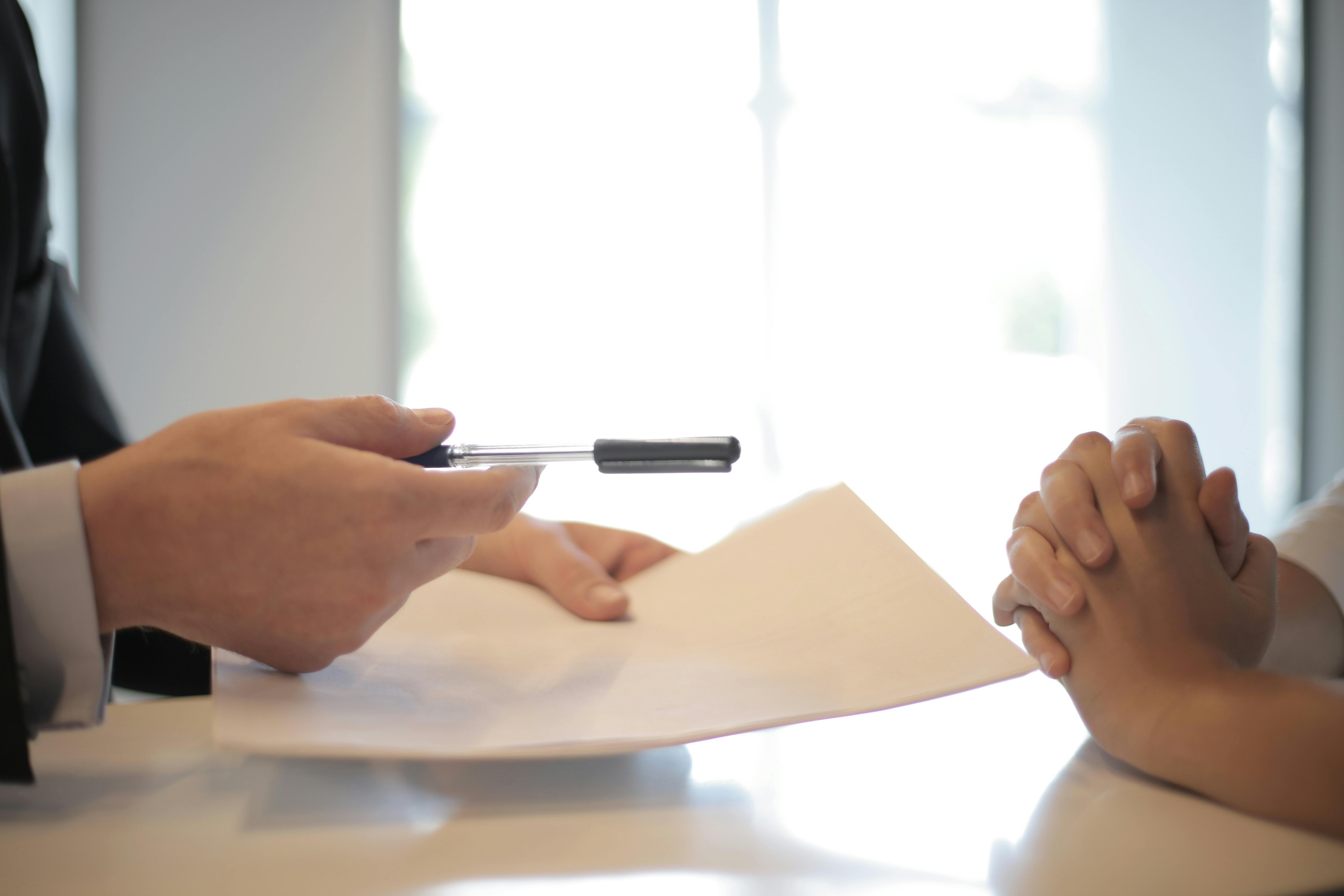 Senior living advisor presenting documents and pen to family member during memory care consultation meeting Senior living advisor presenting documents and pen to family member during memory care consultation meeting
