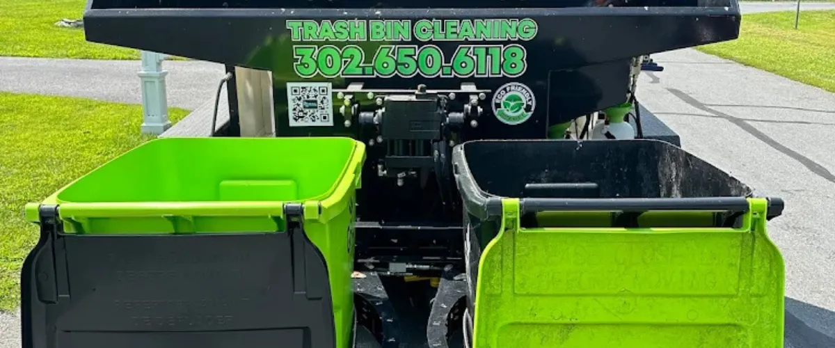 Close-up of R&L Elite Bin Cleaning machine with two green trash bins ready for high-pressure cleaning.