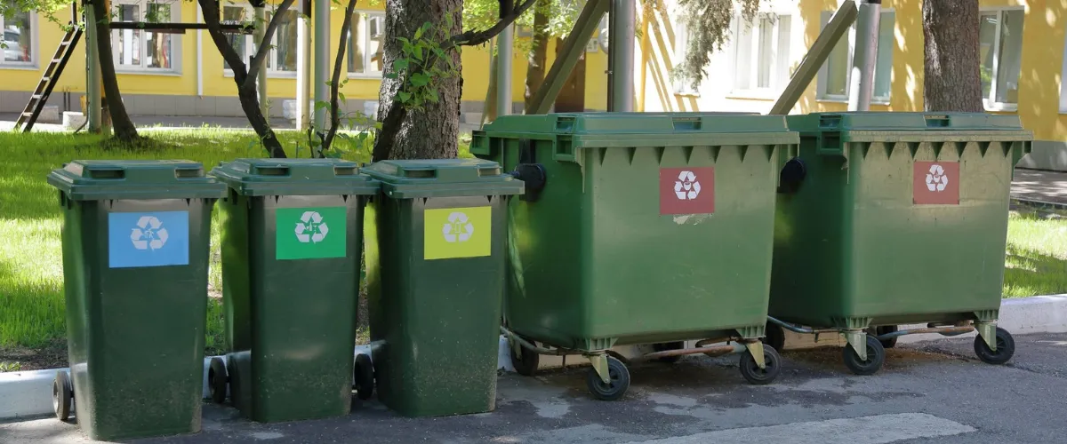 Green recycling dumpsters lined up outdoors for commercial cleaning
