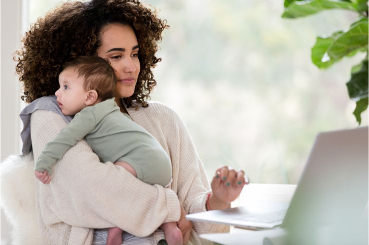 a mother holding her baby while working from home