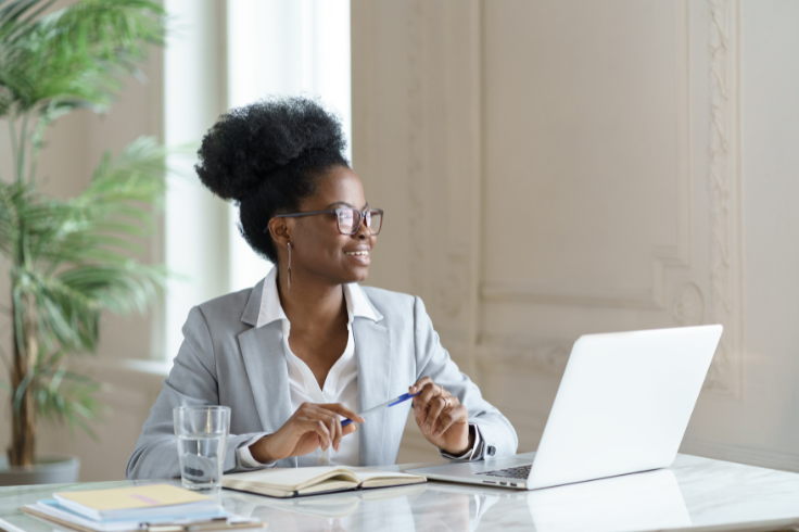 A woman in a business suit sitting at a table with a laptop A woman in a business suit sitting at a table with a laptop