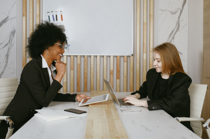 two women in business attire sitting at a table with a laptop - digital marketing for beginners two women in business attire sitting at a table with a laptop - digital marketing for beginners