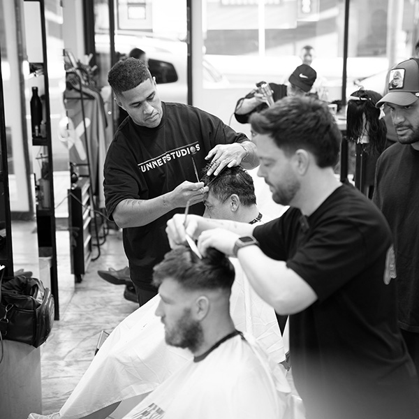Barbering educator teaching students in the the barber academy barbershop Barbering educator teaching students in the the barber academy barbershop