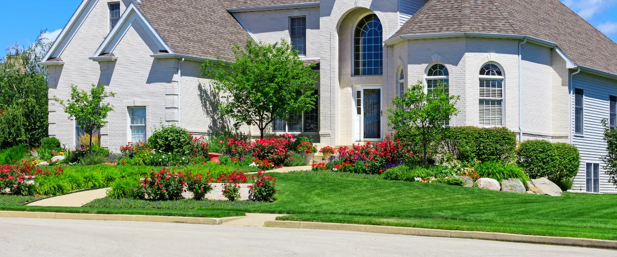 Beautiful luxury home with lush landscaping, manicured lawn, and vibrant flower beds.