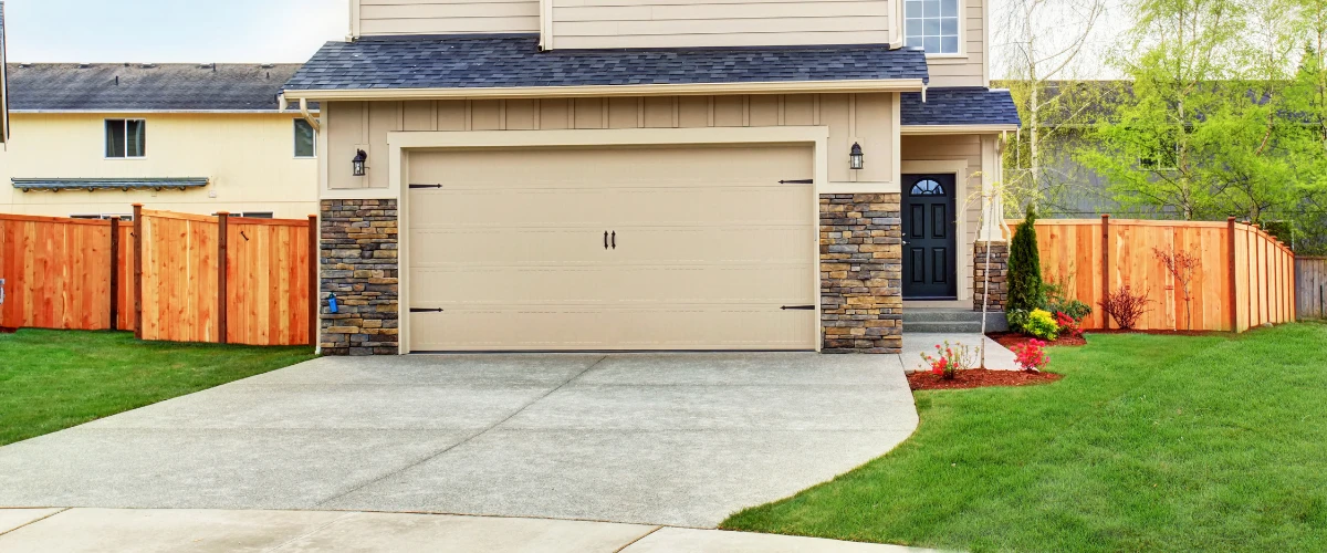 Suburban house with beige garage door and stone accent walls Suburban house with beige garage door and stone accent walls