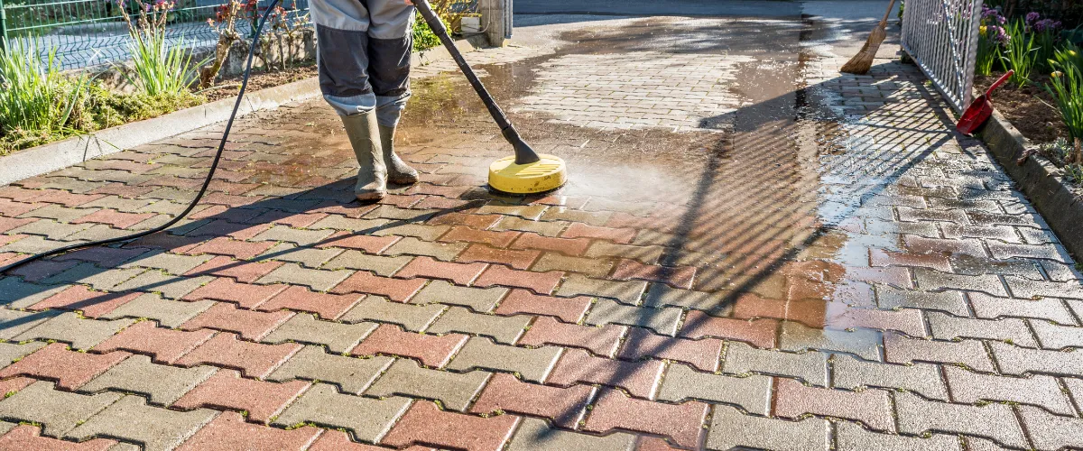 Worker pressure washing a brick driveway, showing dramatic before and after results. Worker pressure washing a brick driveway, showing dramatic before and after results.