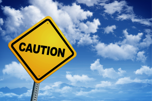 Yellow caution road sign with the word 'CAUTION' in bold black letters, set against a background of a bright blue sky with white clouds. Yellow caution road sign with the word 'CAUTION' in bold black letters, set against a background of a bright blue sky with white clouds.