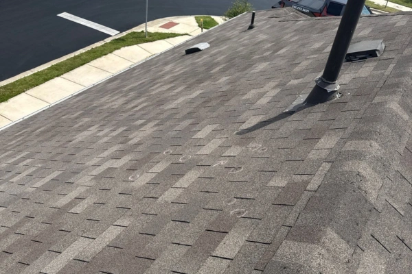 Residential asphalt shingle roof showing chalk markings likely used for identifying hail or storm damage during inspection. Residential asphalt shingle roof showing chalk markings likely used for identifying hail or storm damage during inspection.