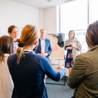 A small group of adult students stand around a flipchart discussing their coursework.