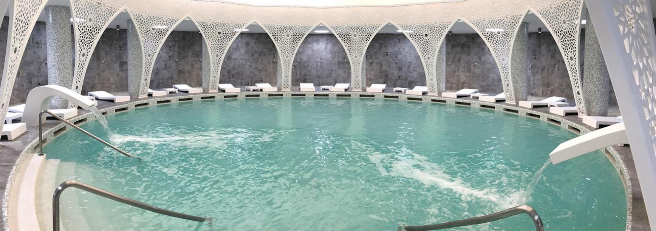 Hillside thermal complex with pale blue soaking pools under a wide sky, set against dry Moroccan terrain. Hillside thermal complex with pale blue soaking pools under a wide sky, set against dry Moroccan terrain.
