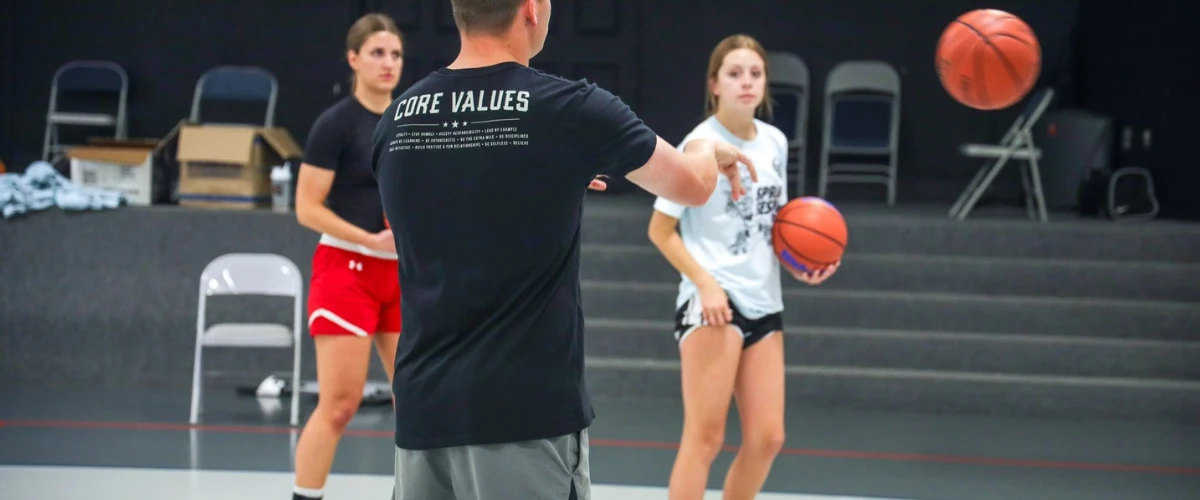 Coach teaching two young basketball players during a practice drill in the gym. Coach teaching two young basketball players during a practice drill in the gym.