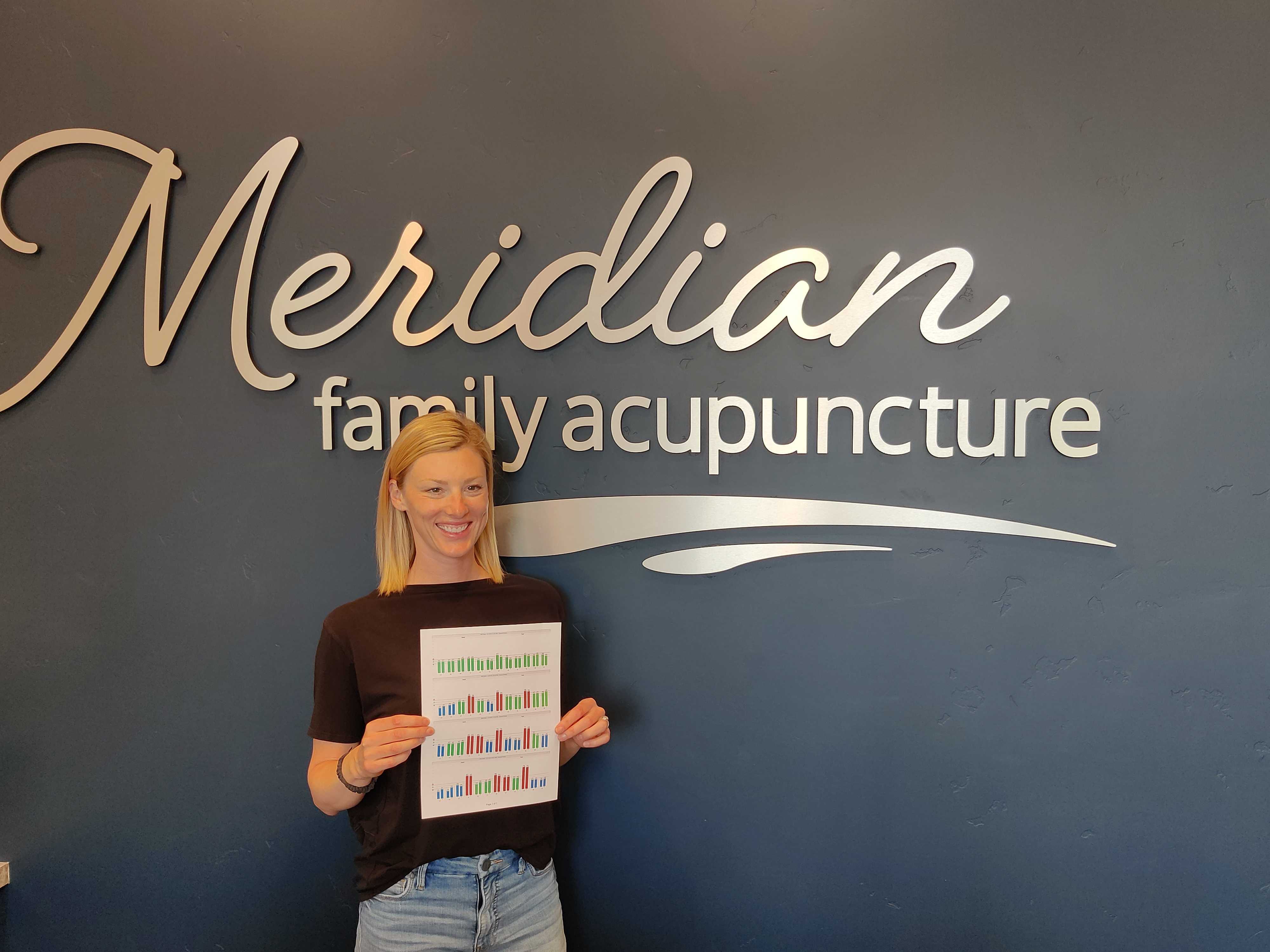 Nikki D, chronic pain patient at Meridian Family Acupuncture, holding her AcuGraph report showing improved balance