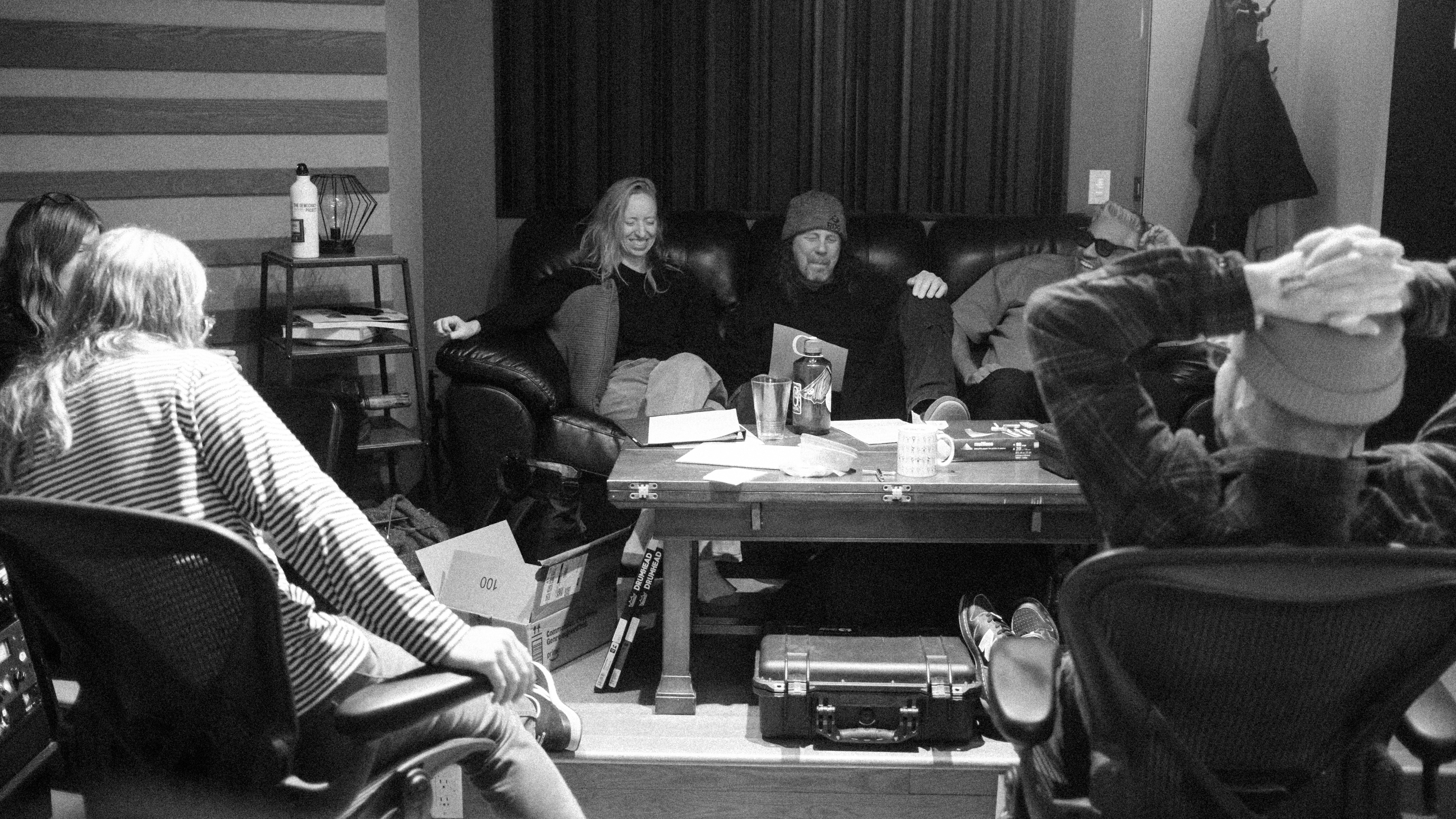 Jamie Wyman and Andy Belski on a couch in the studio with other musicians and the engineer