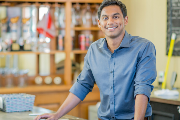 An image of a young business owner in the Airbnb community standing in an office set-up background and smiling in front of the camera. An image of a young business owner in the Airbnb community standing in an office set-up background and smiling in front of the camera.