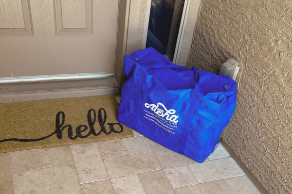 An image of our Aloha-branded, eco-friendly reusable laundry bag placed at a doorstep for delivery. An image of our Aloha-branded, eco-friendly reusable laundry bag placed at a doorstep for delivery.