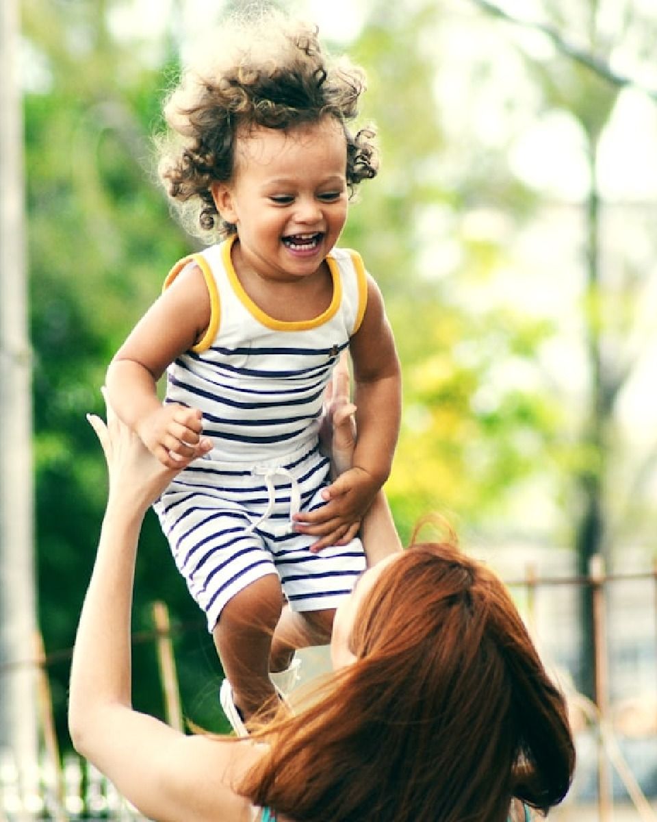 Mom lifting baby up and smiling