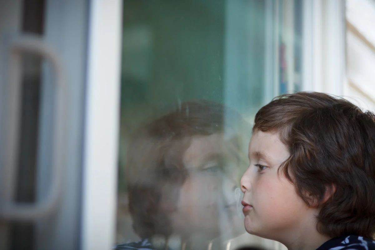 bored boy looking thru glass window bored boy looking thru glass window