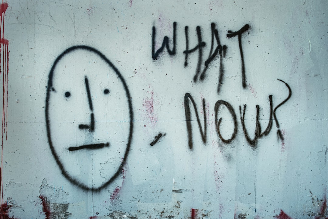 'What Now? and a face spray painted on a wall with