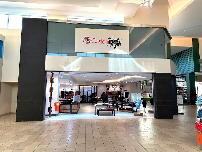 Custom Tees storefront at Cumberland Mall, Houston — open showroom with apparel displays and on-site printing.