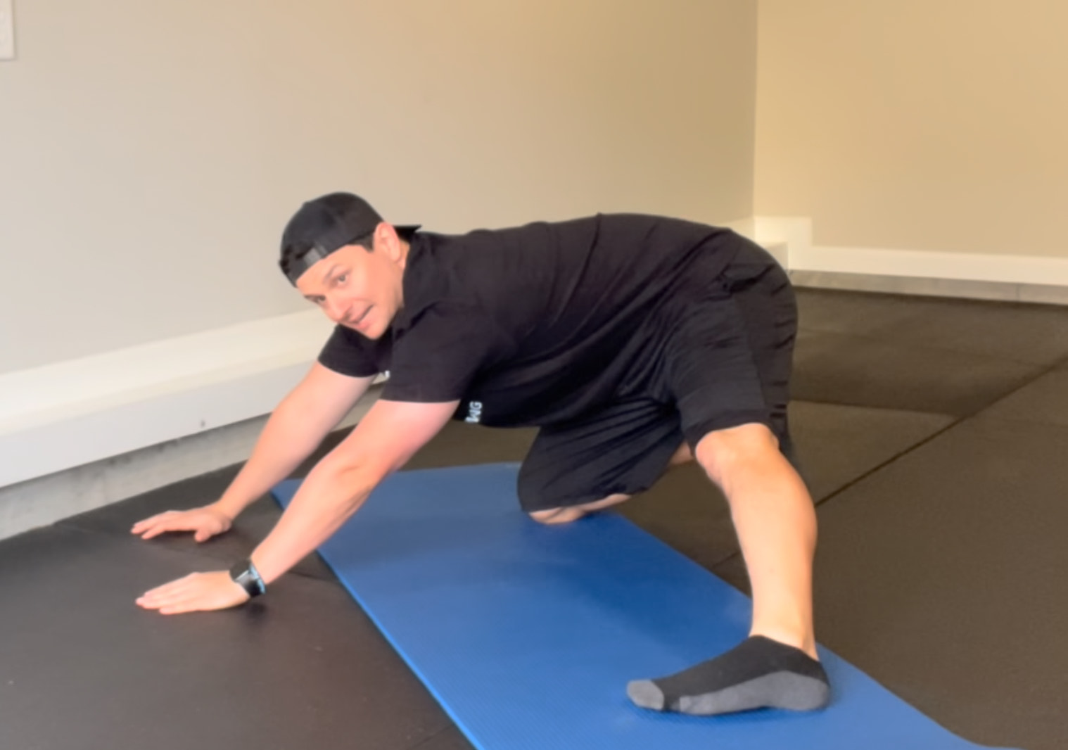 Bryan from FIT40 in a wide-leg kneeling position demonstrating Adductor Rocks, gently rocking hips backward and forward to stretch the inner thighs and improve hip mobility.