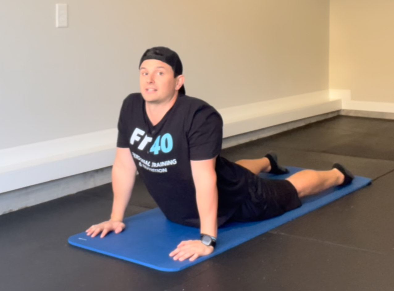 Bryan from FIT40 pressing up from the floor into a Cobra position to open the chest, strengthen the back, and improve spinal mobility.
