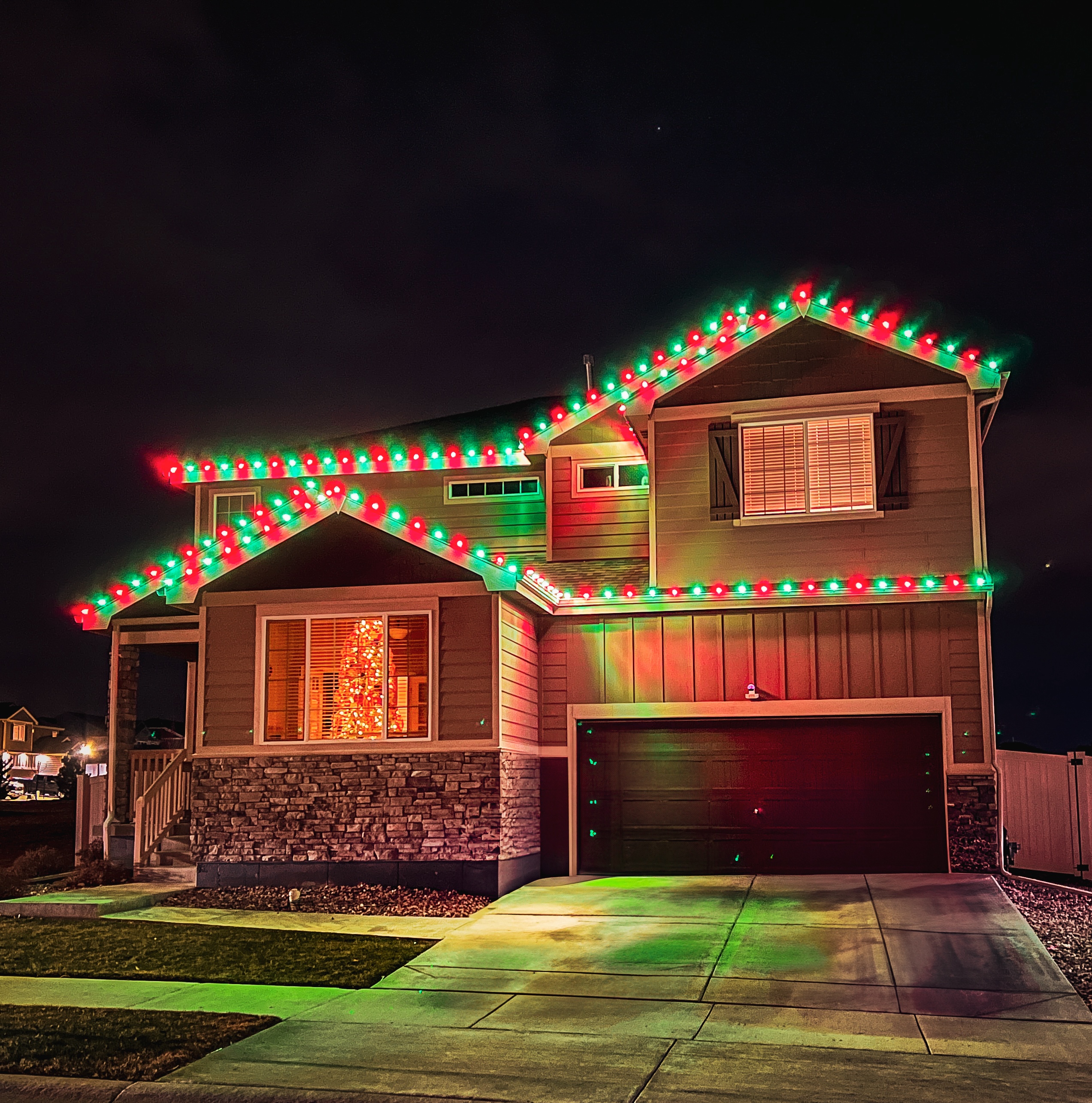 Green and red Christmas light installation on Colorado home