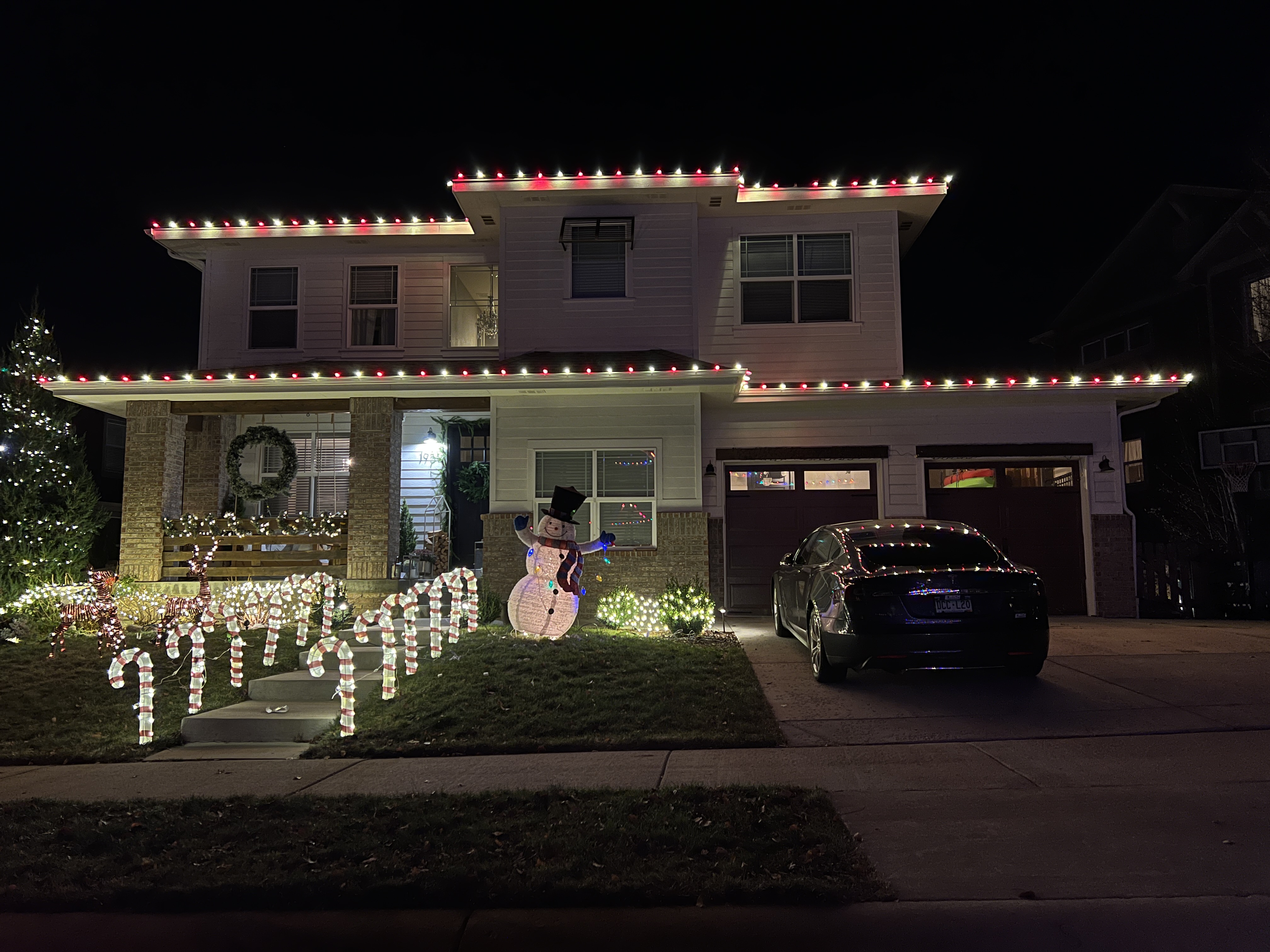Festive warm white and red roofline Christmas lights installed on a Loveland home