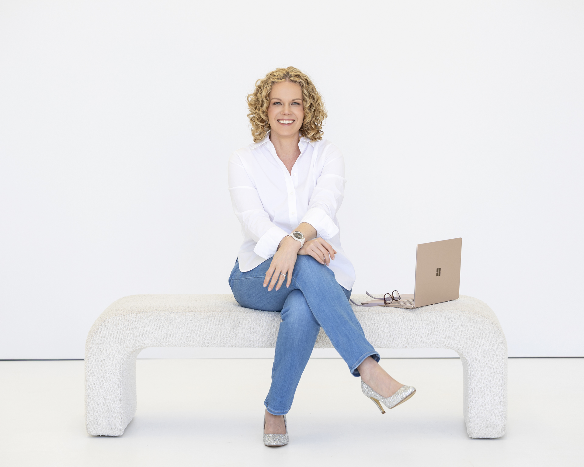 Lady sitting on a bench with one leg crossed over the other and a laptop beside her Alison McWhirter Personal Branding Photography Melbourne