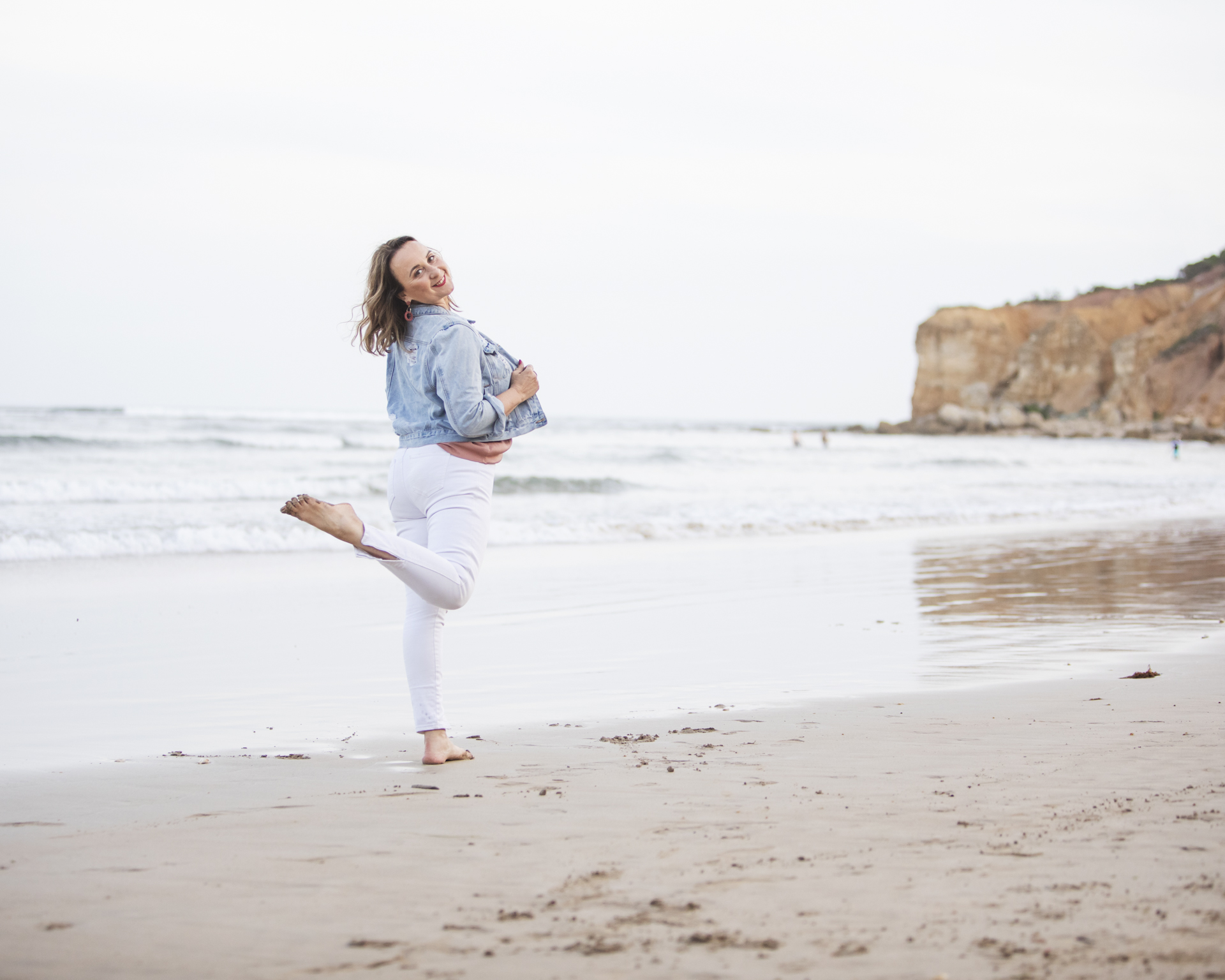 Personal branding image of a lady on a beach kicking up her leg behind her