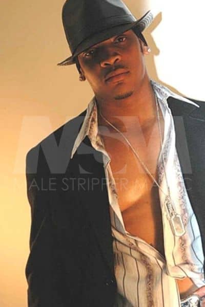 Male stripper Temptation wearing a suit, shirt unbuttoned, and a fedora