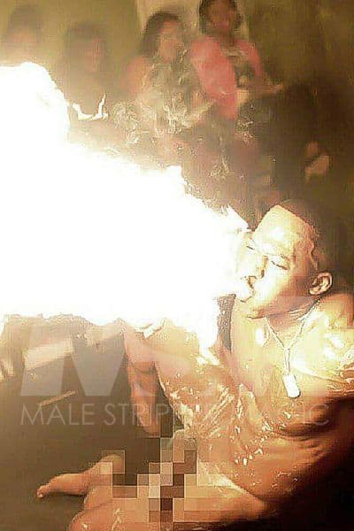 Black male stripper XL performing in a male revue, blowing fire