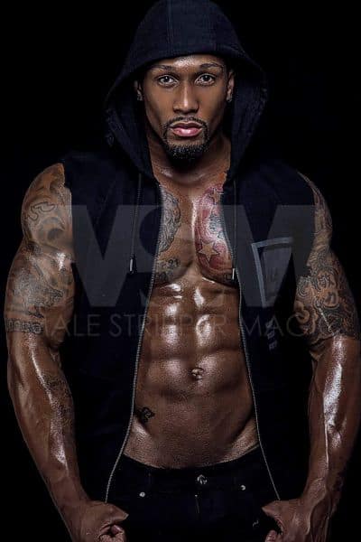 Black Male stripper Pleasure in a dark, mysterious place, shirtless with a black vest, hood, muscular abs