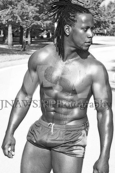 Black male stripper Kingston, muscular, trunks, no shirt, and braids pulled into a ponytail