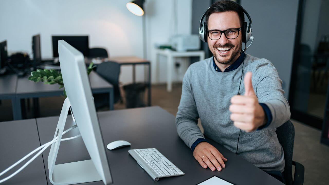 IT specialist giving thumbs up at desktop, representing success with Quick Assist remote support IT specialist giving thumbs up at desktop, representing success with Quick Assist remote support