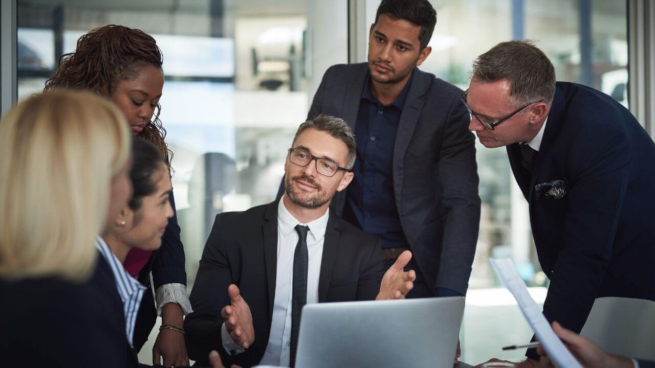 Business team discussing Quick Assist setup and security protocols around a laptop in office Business team discussing Quick Assist setup and security protocols around a laptop in office