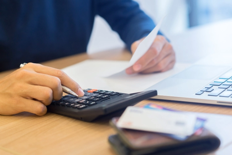`Close-up of hands using calculator and receipt near laptop, illustrating ROI calculation process in cybersecurity budgeting` `Close-up of hands using calculator and receipt near laptop, illustrating ROI calculation process in cybersecurity budgeting`