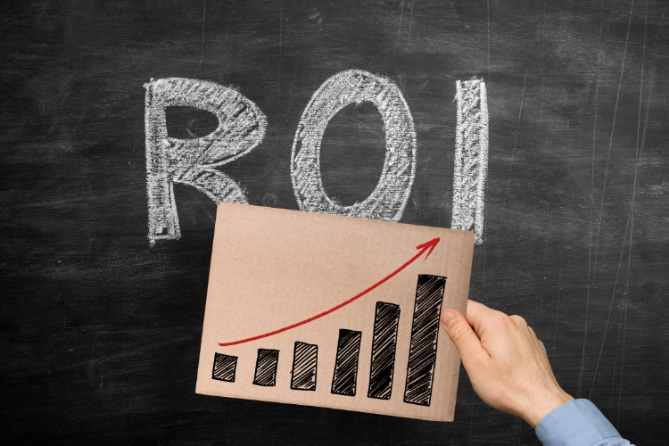 `Hand holding upward trending ROI chart in front of chalkboard, emphasizing financial benefits of cybersecurity investments` `Hand holding upward trending ROI chart in front of chalkboard, emphasizing financial benefits of cybersecurity investments`